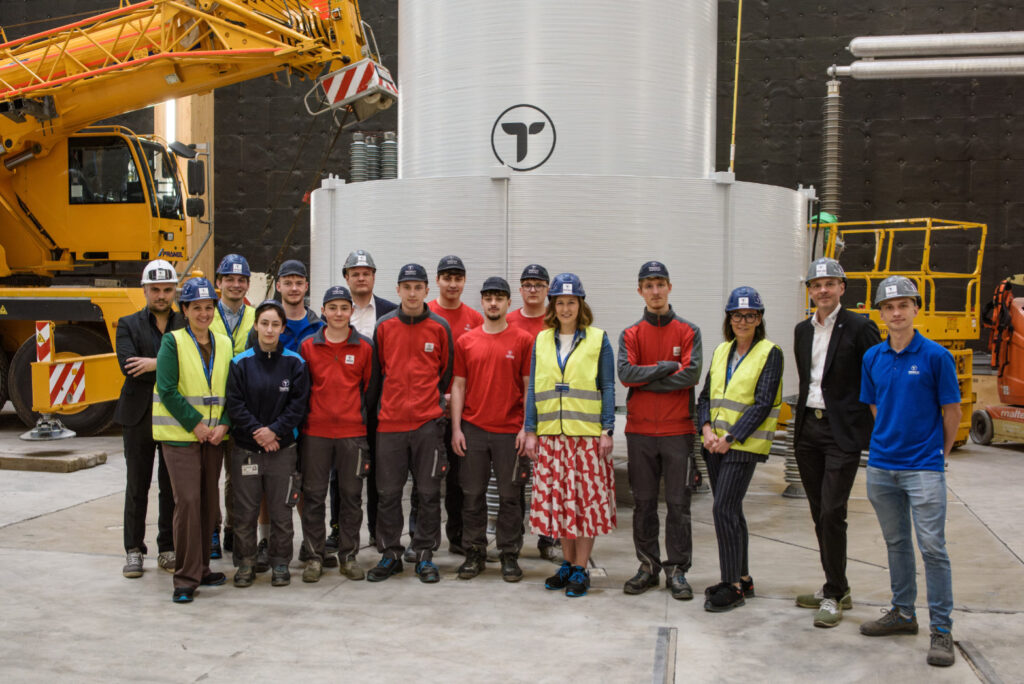 Foto of Trench Austrian apprentices, employees and CEO together with Austrian minister Claudia Bauer, Upper Austria's representative Helena Kirchmayr, Monika Sandberger und Niklas Hager from Zukunft.Lehre.Österreich in front of a air core reactor at the test field